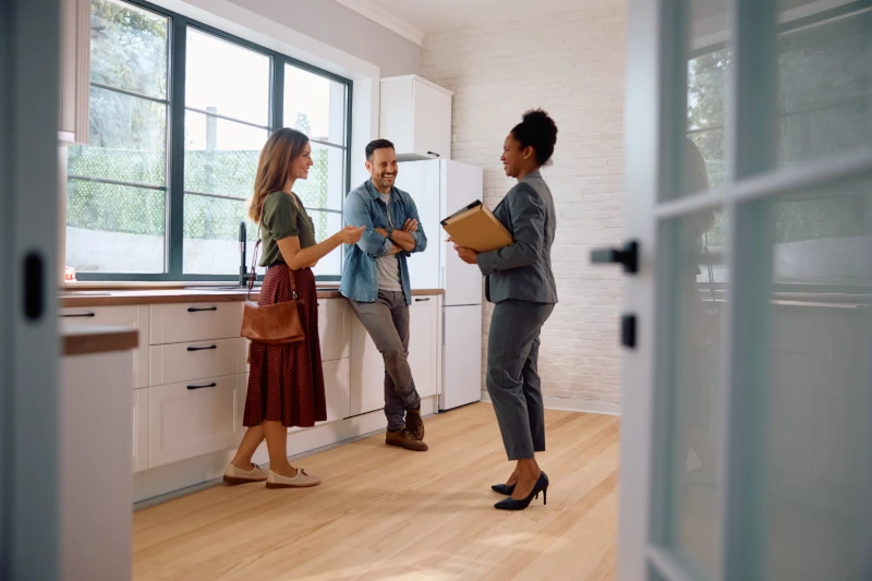 Happy couple taking to real estate agent while buying new home