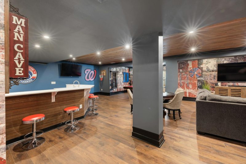 Modern man cave featuring a sleek bar, sports decor, and comfortable seating areas.