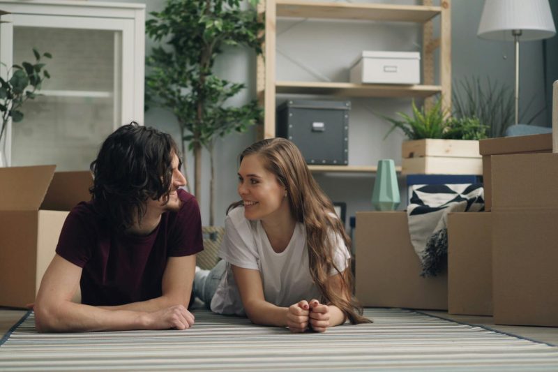 Happy couple relaxing on the floor amid moving boxes in their new home.
