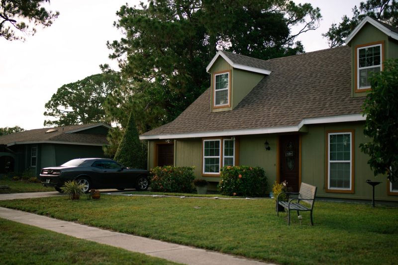 Beautiful suburban home with a green lawn and a parked car, showcasing residential comfort.