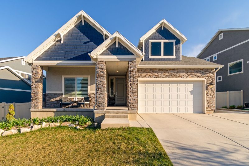 Charming modern suburban home with a stone facade and a neatly maintained green lawn.