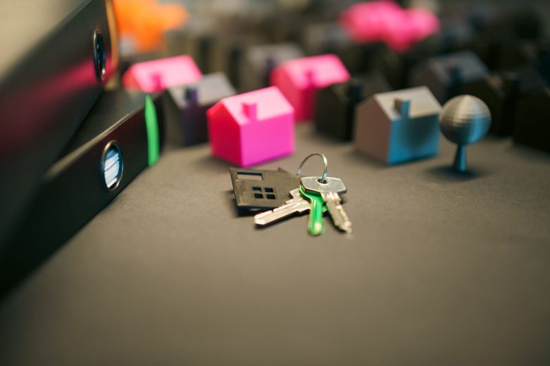 Miniature model houses and a set of keys arranged neatly on a desk.