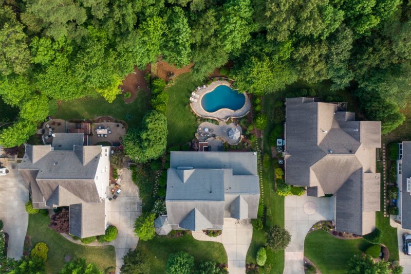 Aerial view of a vibrant suburban neighborhood featuring green backyards and a swimming pool.